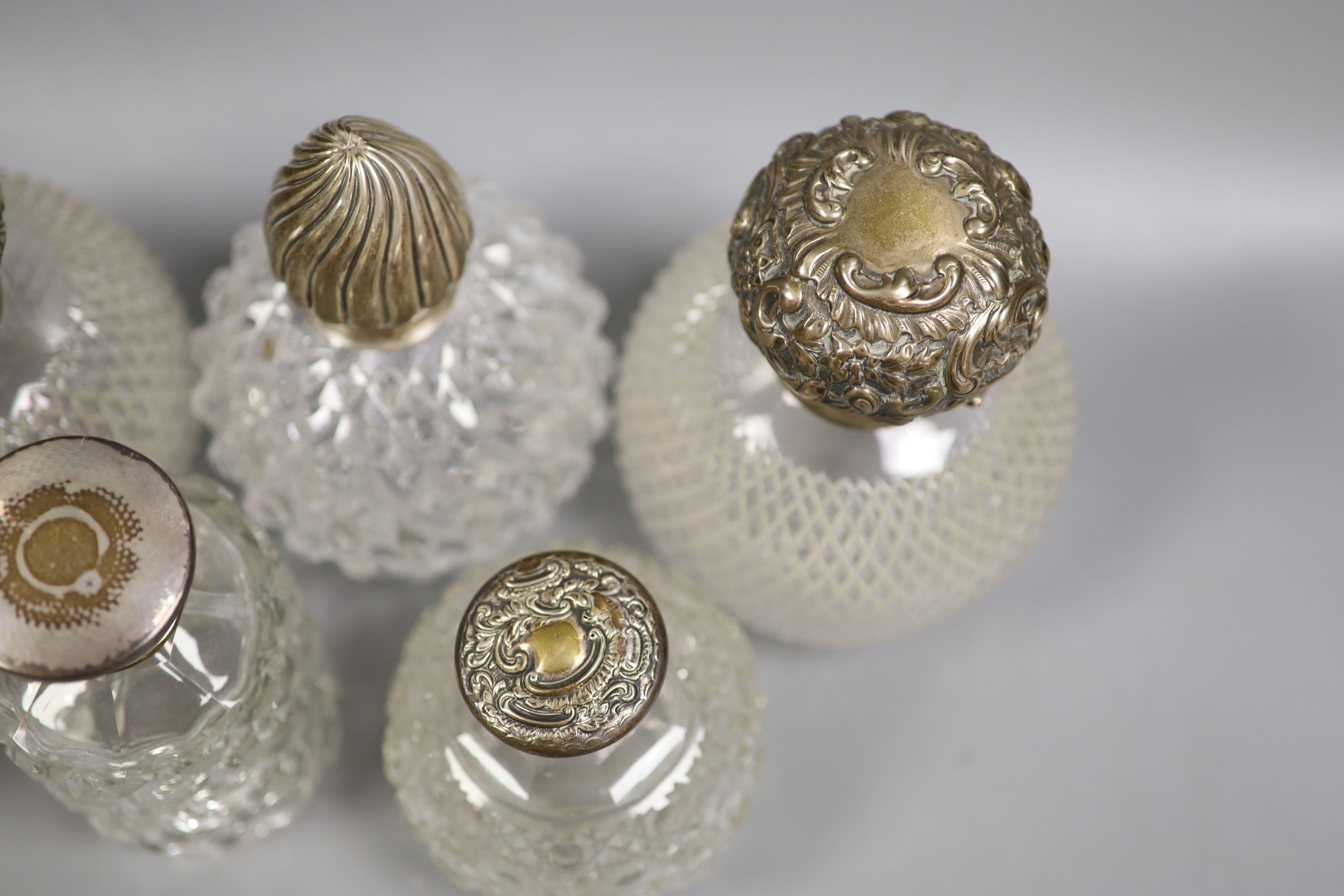 Six assorted silver topped glass scent bottles, including a pair by Chares Stuart Harris, London, 1899, height 14.4cm.